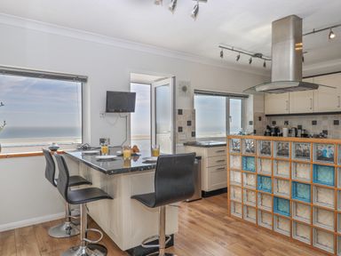A kitchen with a breakfast bar and stools overlooking the sea at Seahaze in Downderry