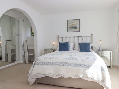 A bedroom with a double bed blue pillows bedside tables and lamps at Seahaze in Downderry