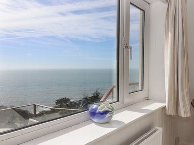 A window with a vase on the sill overlooking the sea and sky at Seahaze Downderry