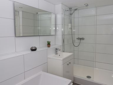 A bathroom with a sink cabinet a shower enclosure and a wall mirror at Seahaze in Downderry