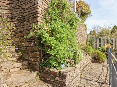 A stone stairway and pathway with green plants and a wooden fence at Seahaze in Downderry
