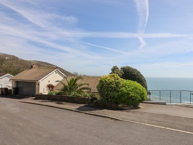 A house with a garage and bushes overlooking the sea at Seahaze in Downderry