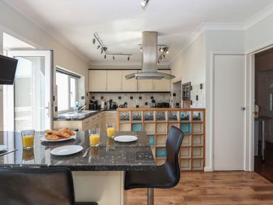 A kitchen with a breakfast bar set with croissants and orange juice at Seahaze in Downderry
