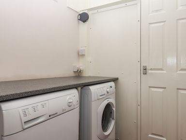 A utility room with a washing machine and dryer under a countertop at Seahaze in Downderry
