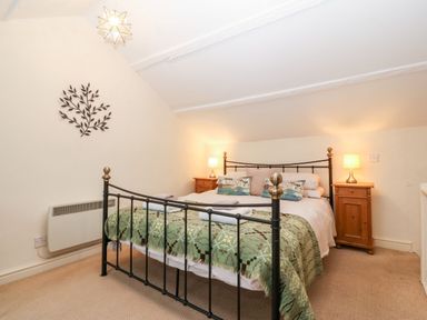 A bedroom with a double bed and bedside tables with lamps at White Lilac Cottage in Brynsiencyn