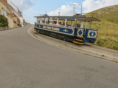 A tramway car with passengers on a hillside tram track near houses and grassy hills at Royal Oak Farm Cottage Betws-y-Coed