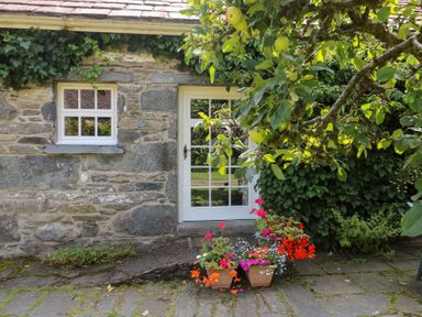 An entrance with flowers and stone wall at Royal Oak Farm Cottage in Betws-y-Coed