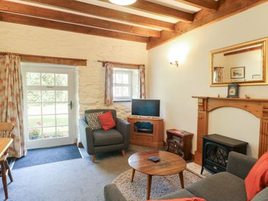 A living room with a sofa and television at Royal Oak Farm Cottage in Betws-y-Coed