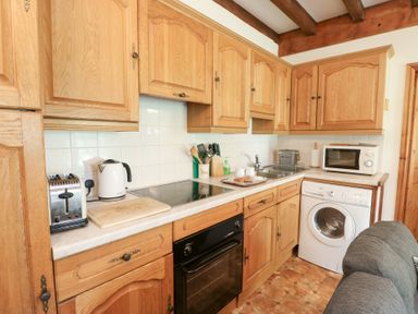 A kitchen with wooden cabinets, appliances and countertop at Royal Oak Farm Cottage Betws-y-Coed