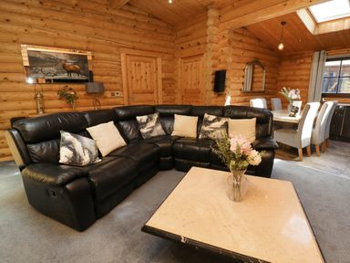 A living room with a black leather sectional sofa and a beige coffee table with flowers at Starwood in Felton