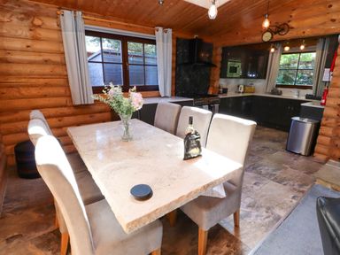 A dining table with six chairs and a vase of flowers in a wooden kitchen at Starwood in Felton