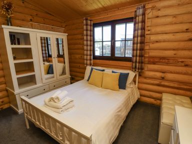 A bedroom with a white bed and folded towels on it next to a window in a wooden cabin at Starwood in Felton