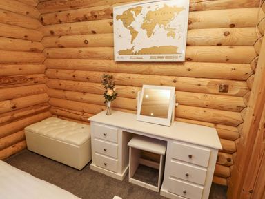 A wooden room with a white dresser a mirror a beige ottoman and a map on the wall at Starwood in Felton