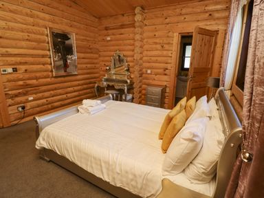 A bedroom with a bed pillows a dressing table and wooden walls at Starwood Felton