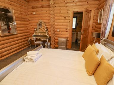 A bedroom with a bed that has yellow pillows and folded towels a wooden wall with a decorative mirror and chair and an open door leading to a bathroom at Starwood in Felton