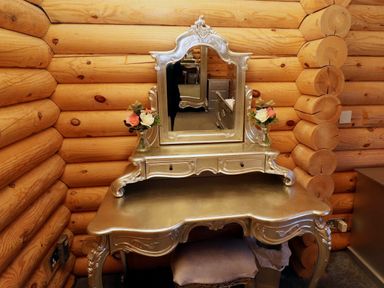 A dressing table with a mirror and flower vases in a log cabin room at Starwood in Felton
