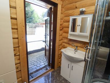 A bathroom with a white sink cabinet a glass shower door and a wooden door leading outside at Starwood in Felton
