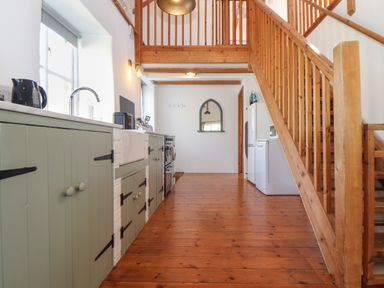 A kitchen with wooden stairs green cabinets a white refrigerator and a sink at Joe's Barn in Mullion