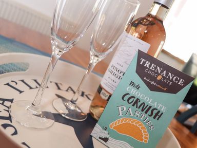 A tray with two empty wine glasses a bottle of pinot grigio and a box of milk chocolate cornish pasties at Berts Barn in Mullion