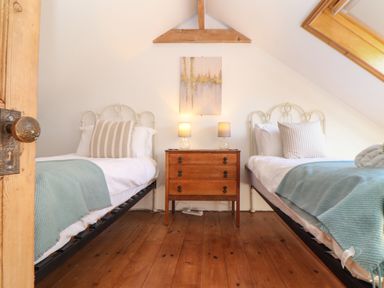 A bedroom with two single beds and a wooden dresser with lamps at Bert's Barn in Mullion