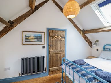 A bedroom with a blue metal bed frame wooden door a radiator and skylight at Pengarreg in Barmouth