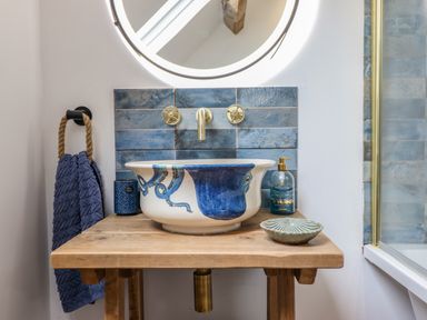 A bathroom sink with blue octopus design on a wooden countertop with blue tile backsplash at Pengarreg in Barmouth