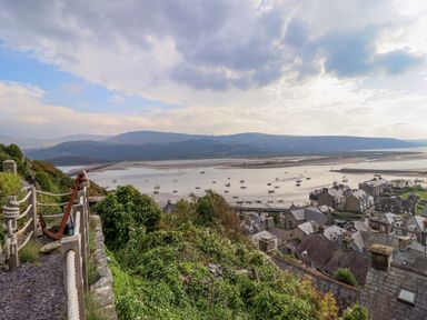 A view of a coastal town with boats on water and hills in the background at Pengarreg in Barmouth