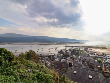 A coastal town with boats in the water and hills in the background at Pengarreg in Barmouth