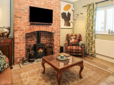 A living room with a brick fireplace armchair patterned curtains and a wooden coffee table at Sunflowers in Earsdon near Whitley Bay