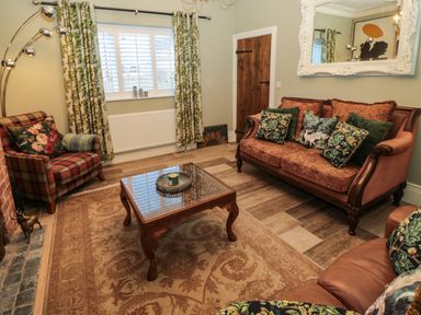 A living room with patterned curtains sofas a wooden coffee table and a large wall mirror at Sunflowers in Earsdon near Whitley Bay