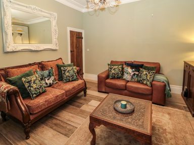 A living room with two sofas a wooden coffee table and a large mirror at Sunflowers in Earsdon near Whitley Bay