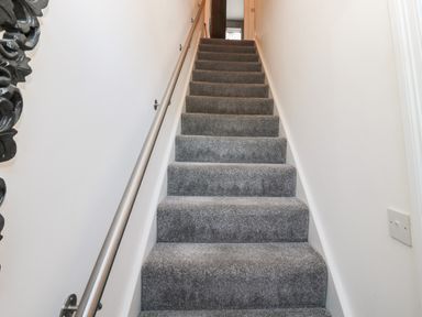 A staircase with grey carpet and metal handrail at Sunflowers in Earsdon near Whitley Bay