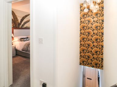 A hallway with stairs leading down and a bedroom visible through a doorway with a bed and wall mural at Sunflowers in Earsdon near Whitley Bay