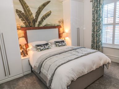 A bedroom with a double bed bedside lamps and white wardrobes at Sunflowers in Earsdon near Whitley Bay