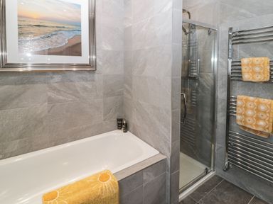 A bathroom with a bathtub a shower and yellow towels at Sunflowers in Earsdon near Whitley Bay