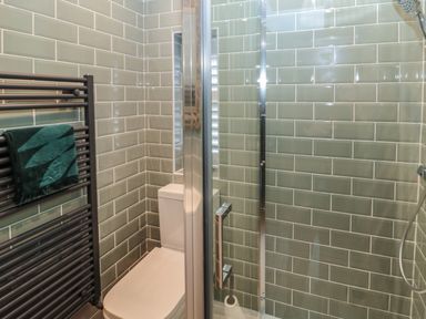 A bathroom with a toilet a glass shower enclosure and a heated towel rail with a towel at Sunflowers in Earsdon near Whitley Bay