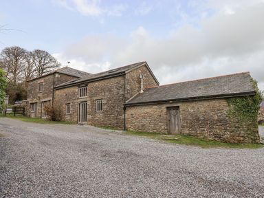 A stone barn with multiple windows and doors on a gravel driveway at Brimpts Barn Dartmeet near Princetown