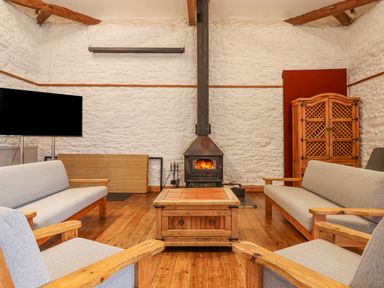 A living room with wooden furniture a wood burning stove and a television at Brimpts Barn Dartmeet near Princetown