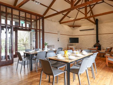 A dining area with tables set for a meal and a seating area with chairs and a fireplace at Brimpts Barn in Dartmeet near Princetown