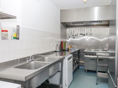 A kitchen with a double sink stainless steel counters hanging utensils and cooking appliances at Brimpts Barn Dartmeet near Princetown