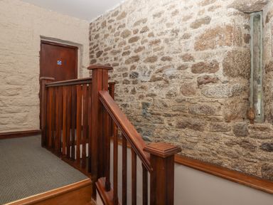 A staircase with wooden railing and stone walls at Brimpts Barn Dartmeet near Princetown