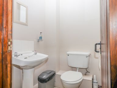 A small bathroom with a white sink toilet and trash bin at Brimpts Barn Dartmeet near Princetown