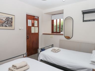 A bedroom with two single beds towels on beds a mirror on the wall and a wooden door at Brimpts Barn Dartmeet near Princetown