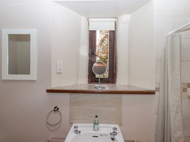 A bathroom with a sink mirror shelf window and shower curtain at Brimpts Barn in Dartmeet near Princetown