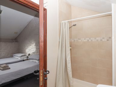 A bathroom with a tiled shower and a door open to a bedroom with two single beds at Brimpts Barn Dartmeet near Princetown