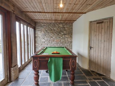 A room with a pool table a stone wall wooden ceiling and a door labeled sauna at Brimpts Barn Dartmeet near Princetown