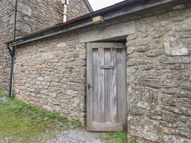A wooden door with a sign reading Drying Room set in a stone wall outside a building at Brimpts Barn Dartmeet near Princetown