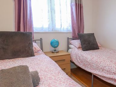 A bedroom with two single beds a bedside table and a globe at Cornish Holiday at Atlantic Bays in St Merryn