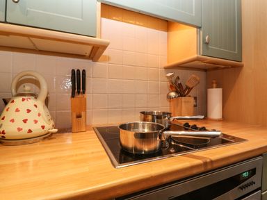A kitchen counter with a kettle knives cooking utensils pots and a stove at Lavender Cottage in Coniston