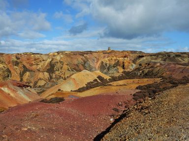A landscape with multicolored hills and rocky terrain under a cloudy sky
